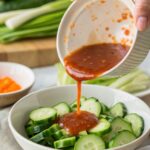 Colorful Thai cucumber salad with thin cucumber ribbons, crushed peanuts, and fresh cilantro in a white bowl