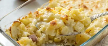 Baked potato onion casserole in white dish with golden melted cheese on top and visible layers of tender potatoes and onions