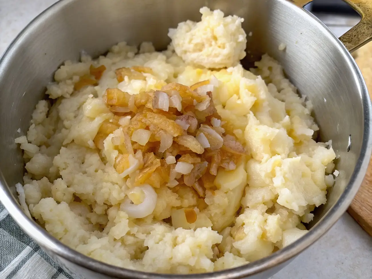 Baked potato onion casserole in white dish with golden melted cheese on top and visible layers of tender potatoes and onions