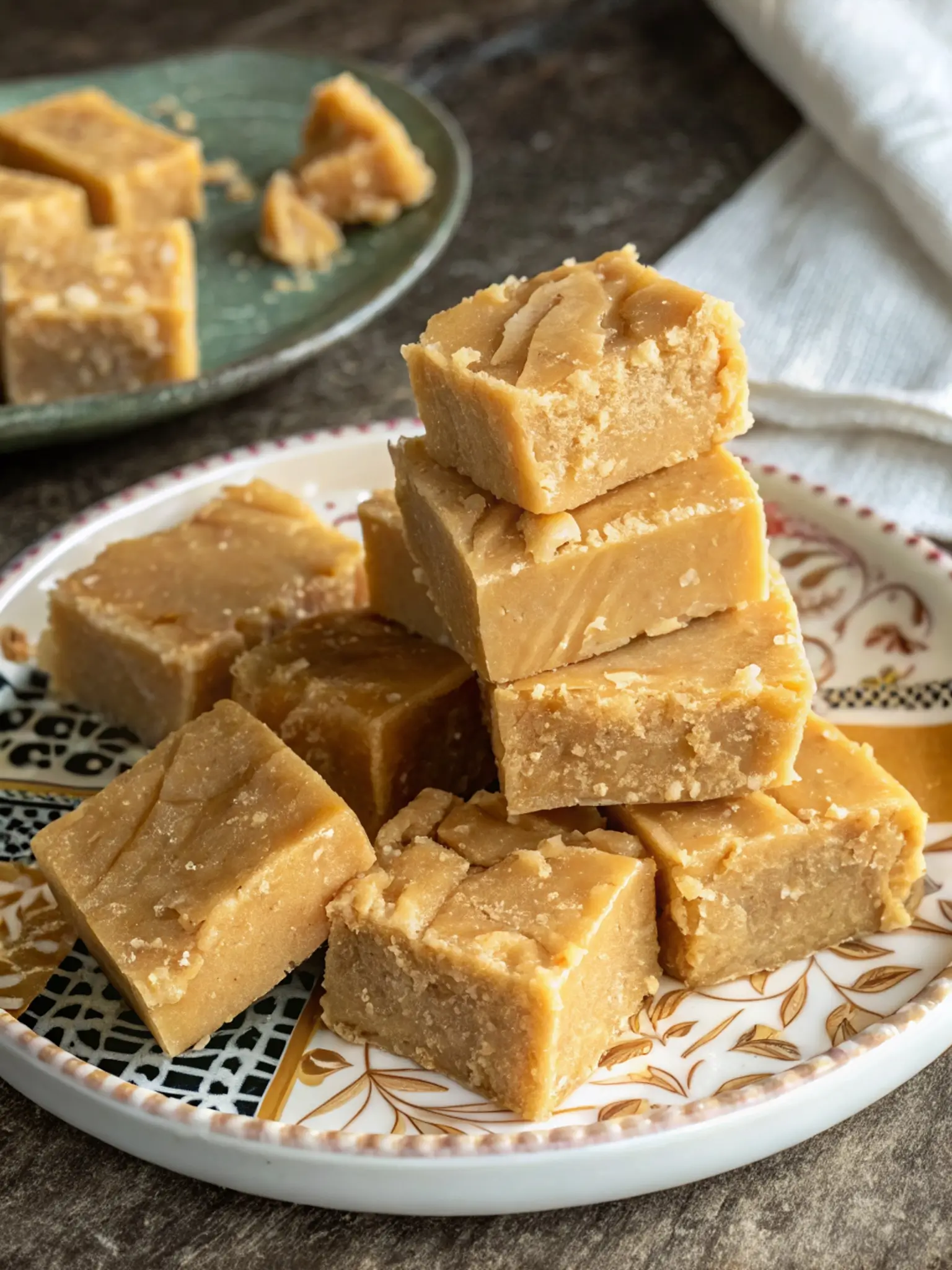 Golden brown Scottish tablet candy cut into small squares on parchment paper showing crumbly texture