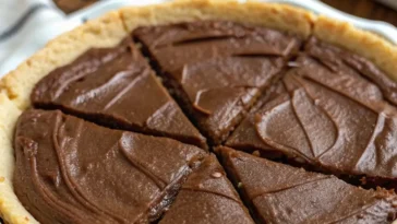 Slice of rich chocolate pie with whipped cream topping and chocolate shavings on a white plate with a fork