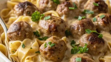 Swedish meatball noodle bake casserole in white dish with golden cheese topping and egg noodles