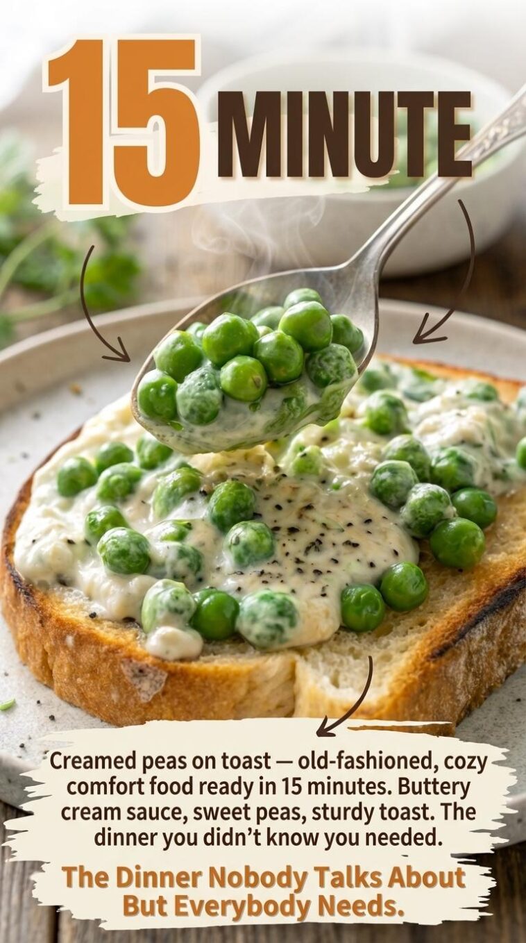 A wooden spoon stirring bright green frozen peas into a bubbling cream sauce in a small saucepan on a gas stovetop.